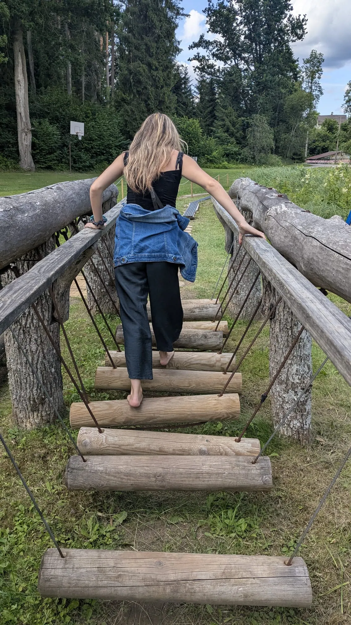 A visitor crossing a wooden balance bridge on the barefoot trail