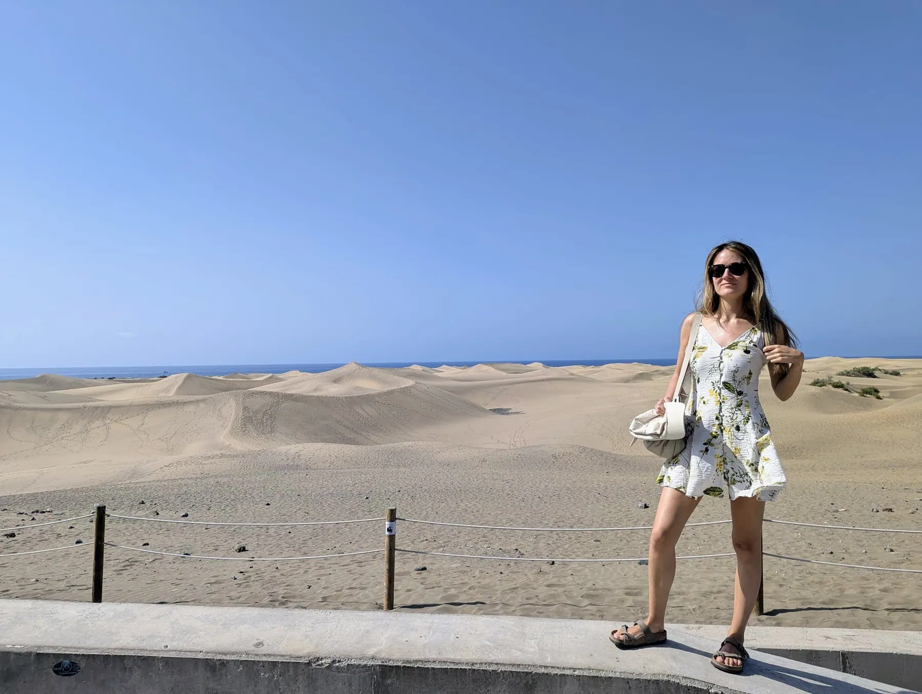 A traveller standing above the pale sand dunes of Maspalomas with the Atlantic beyond