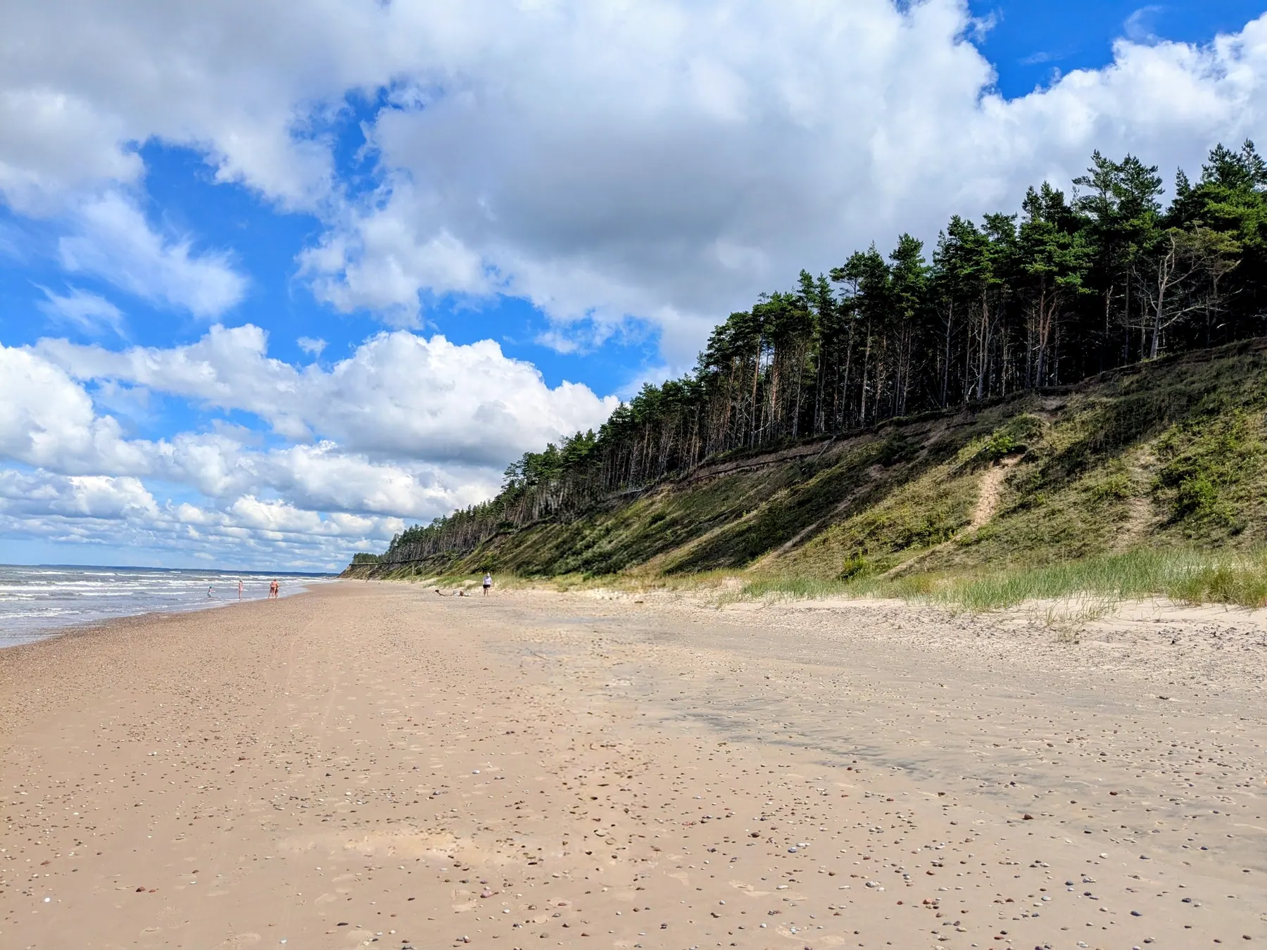 The broad empty beach and high sandy coast of Jūrkalne beneath a blue sky