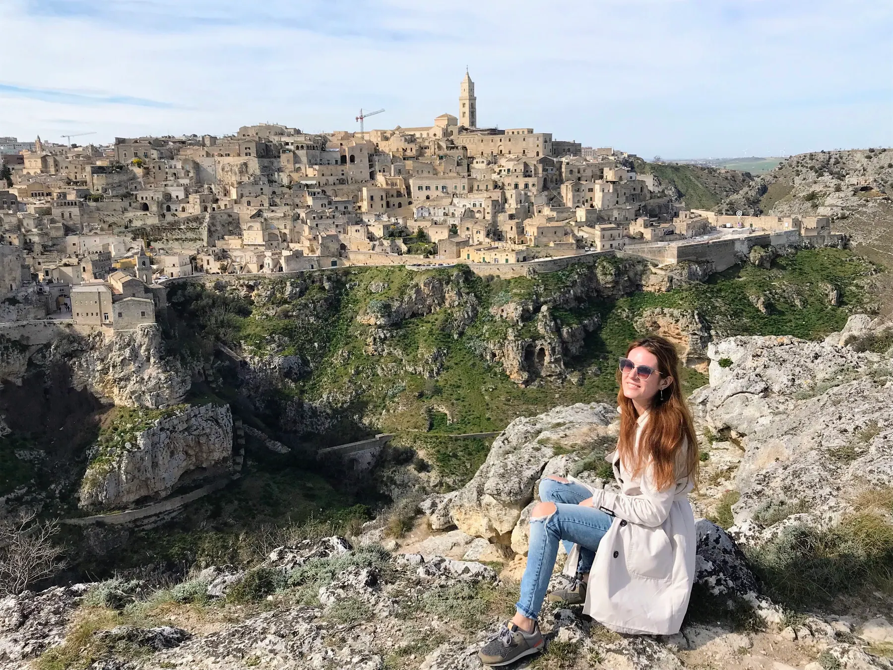 A traveler among the Murgia rocks with Matera behind