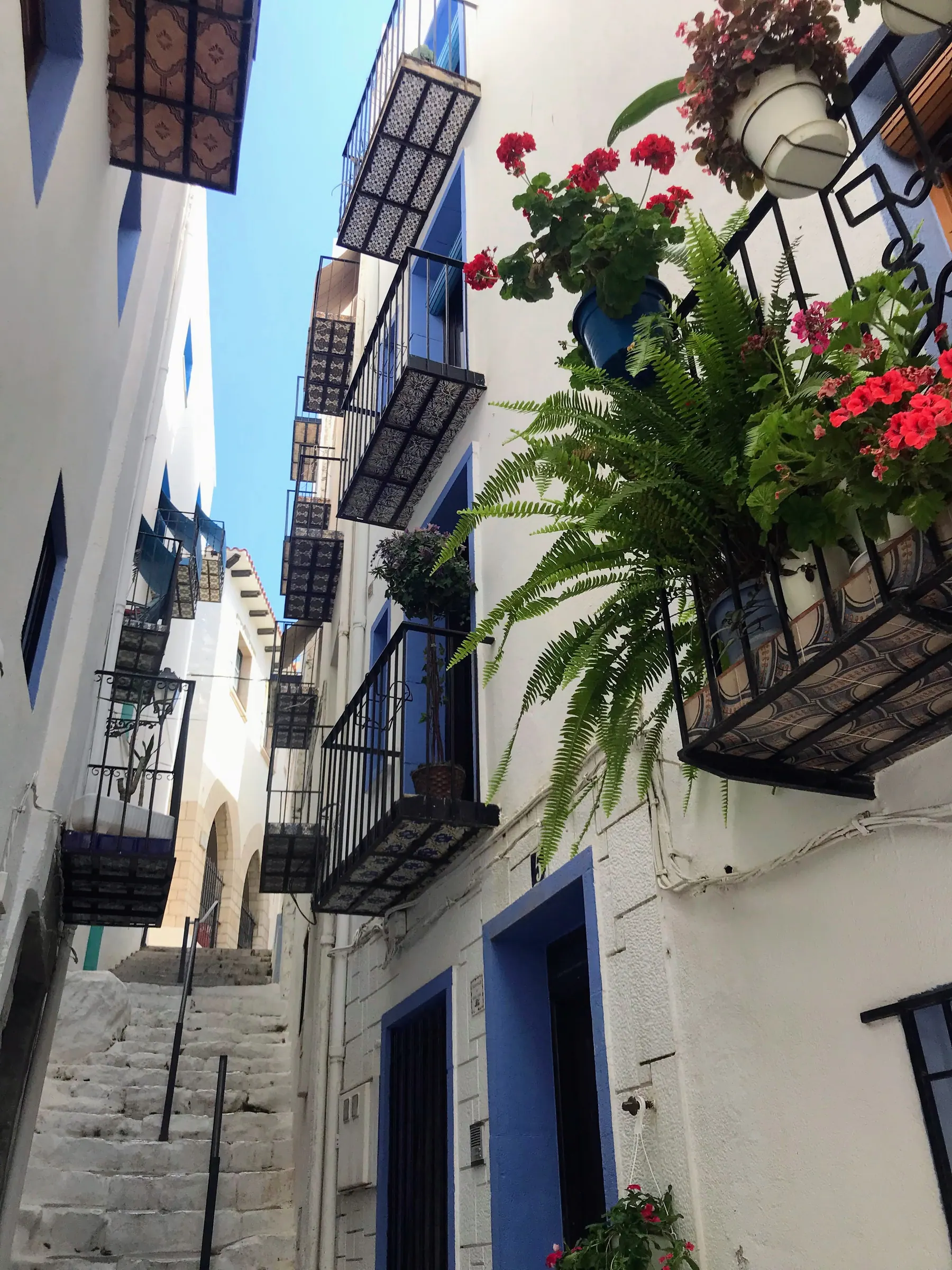 Narrow whitewashed street with balconies and flowers in Peñíscola old town