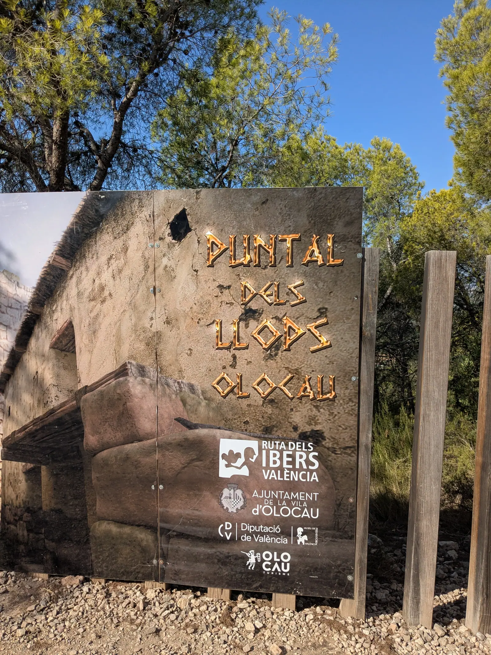 Wooden Puntal dels Llops sign among pine trees near Olocau